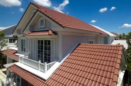 A two story home with a red tile roof and a white balcony