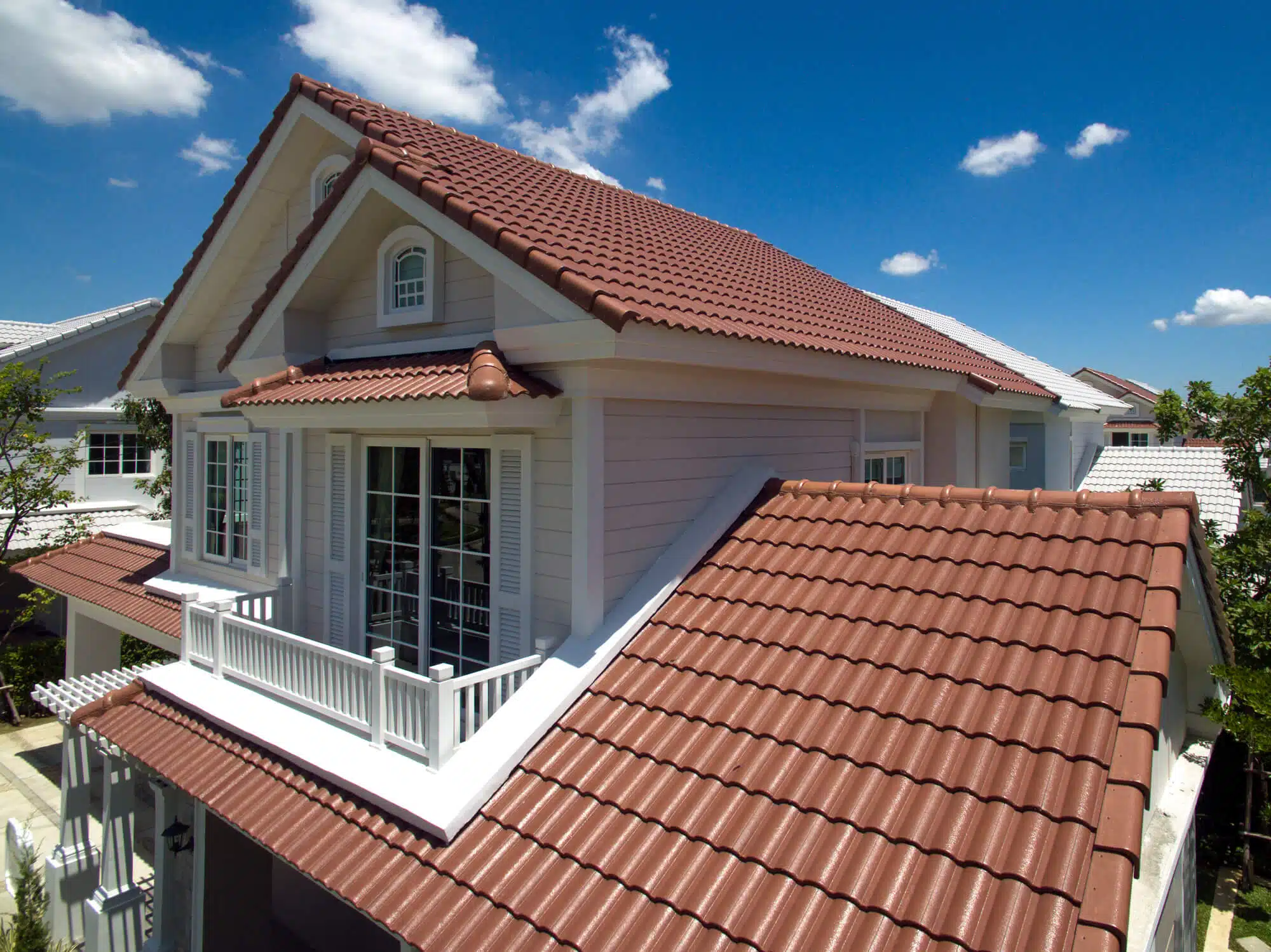 A two story home with a red tile roof and a white balcony
