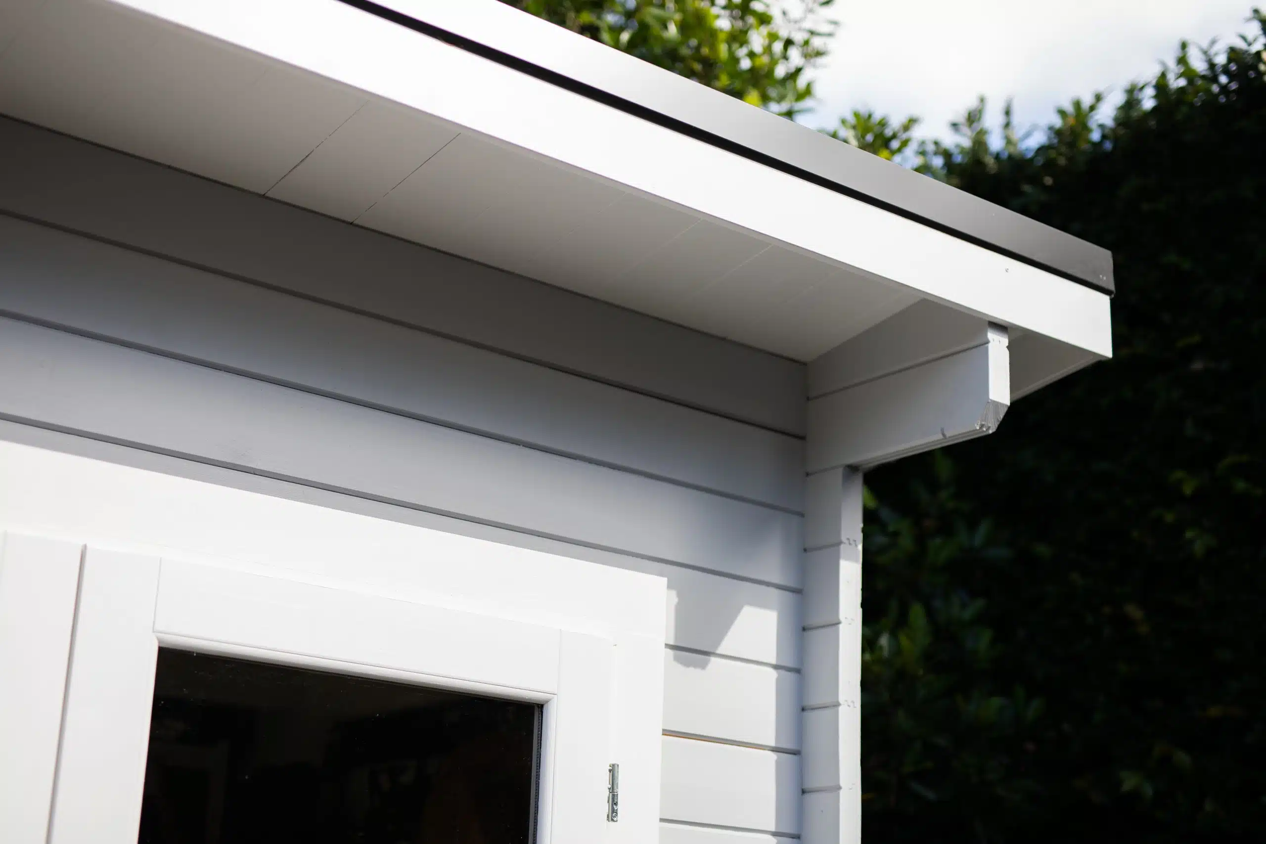 Water stain trail on white fascia board directly below a gutter overflow point on a two-story New Orleans house