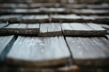 Close-up of weathered grey cedar shakes on a roof showing split wood grain and thick butt ends