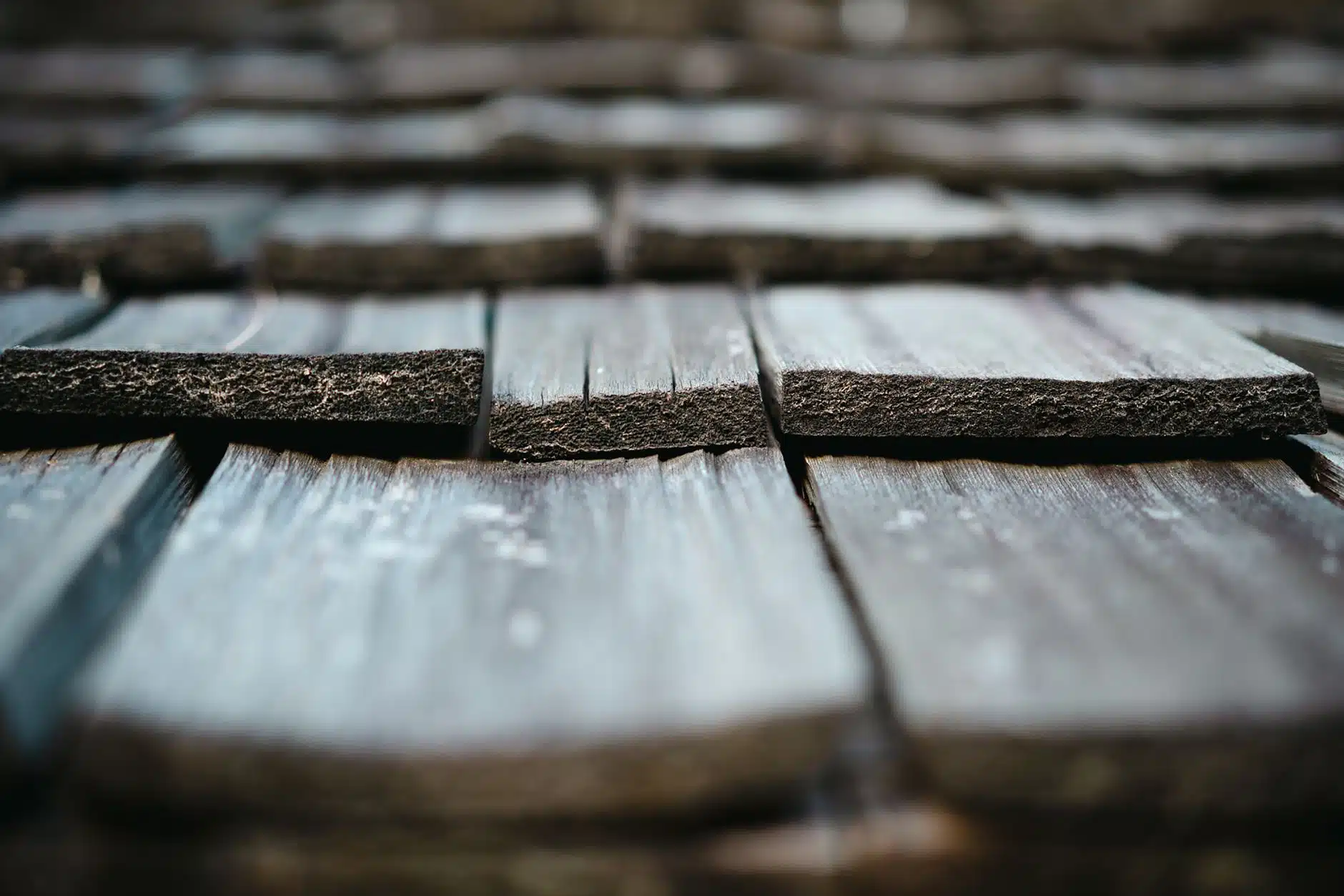 Close-up of weathered grey cedar shakes on a roof showing split wood grain and thick butt ends